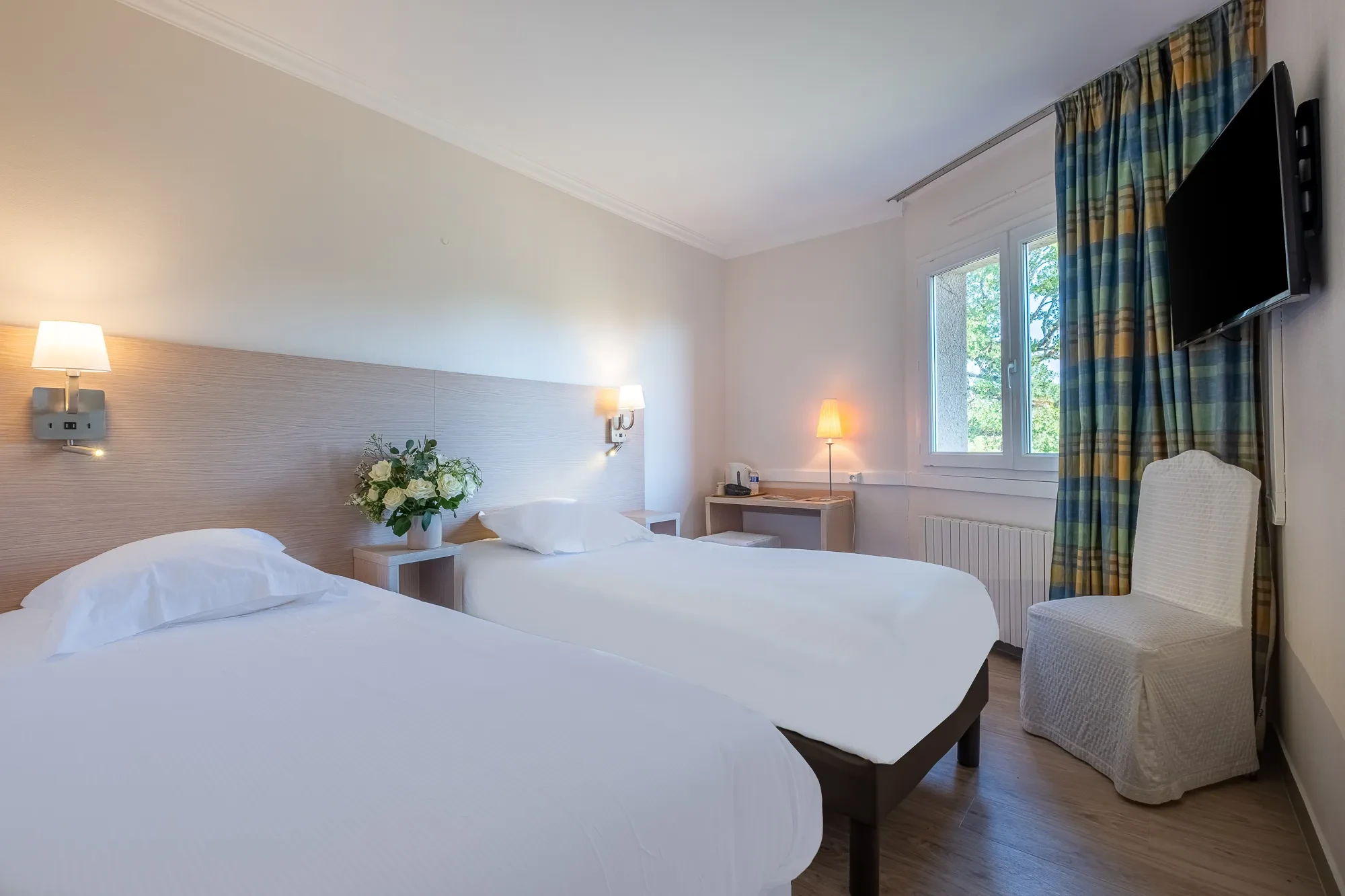 Chambre d'hôtel lumineuse avec deux lits simples
