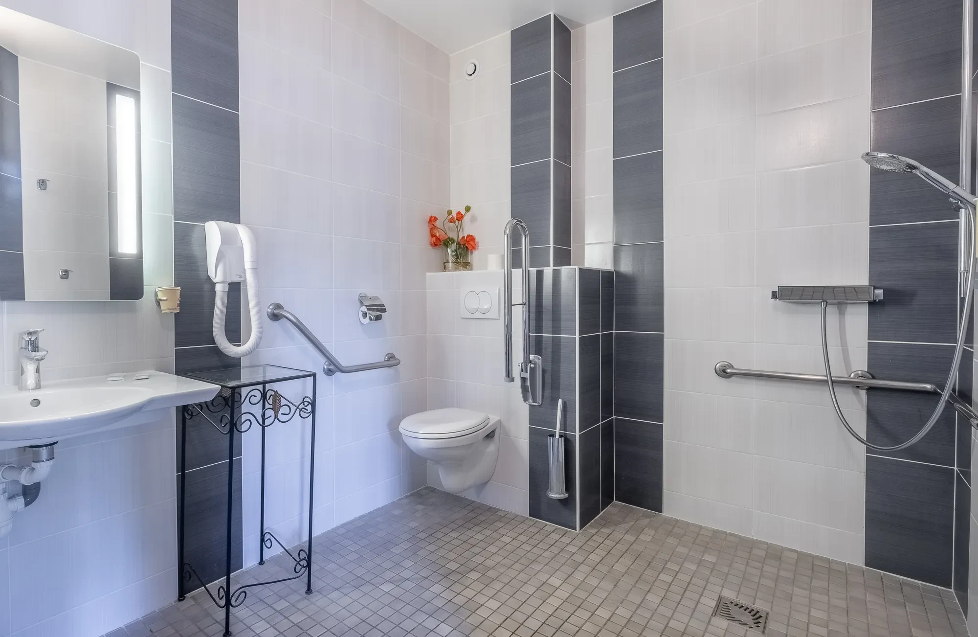 Salle de bain accessible avec douche et barres d'appui