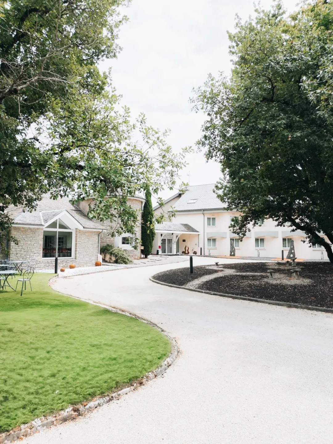 Entrée d’une maison entourée d’arbres et pelouse