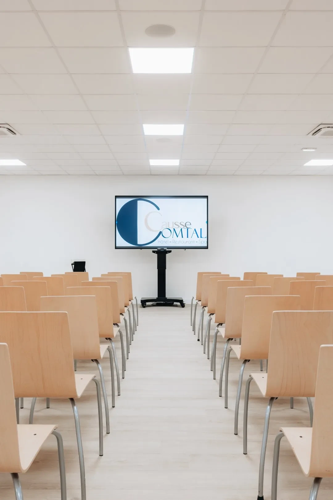 Salle de conférence moderne avec écran et chaises.