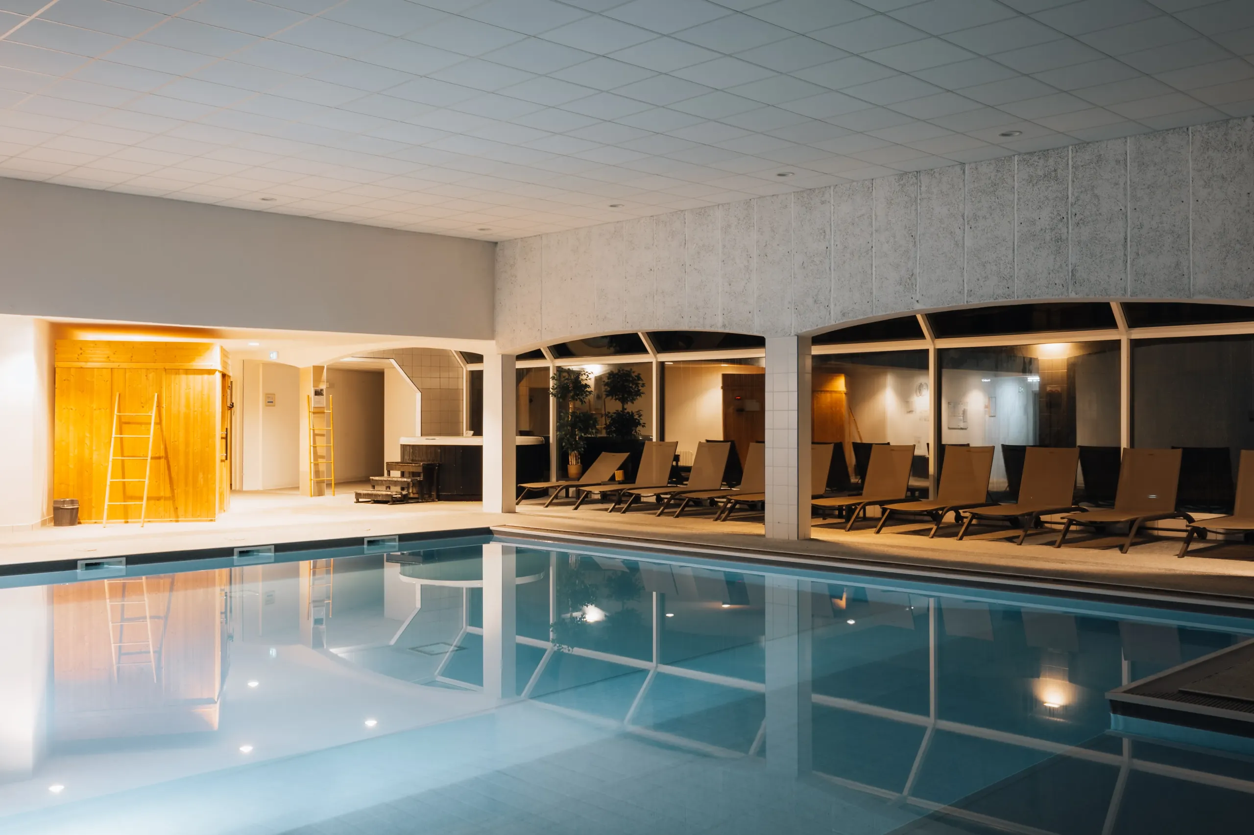 Piscine intérieure avec transats et éclairage chaleureux