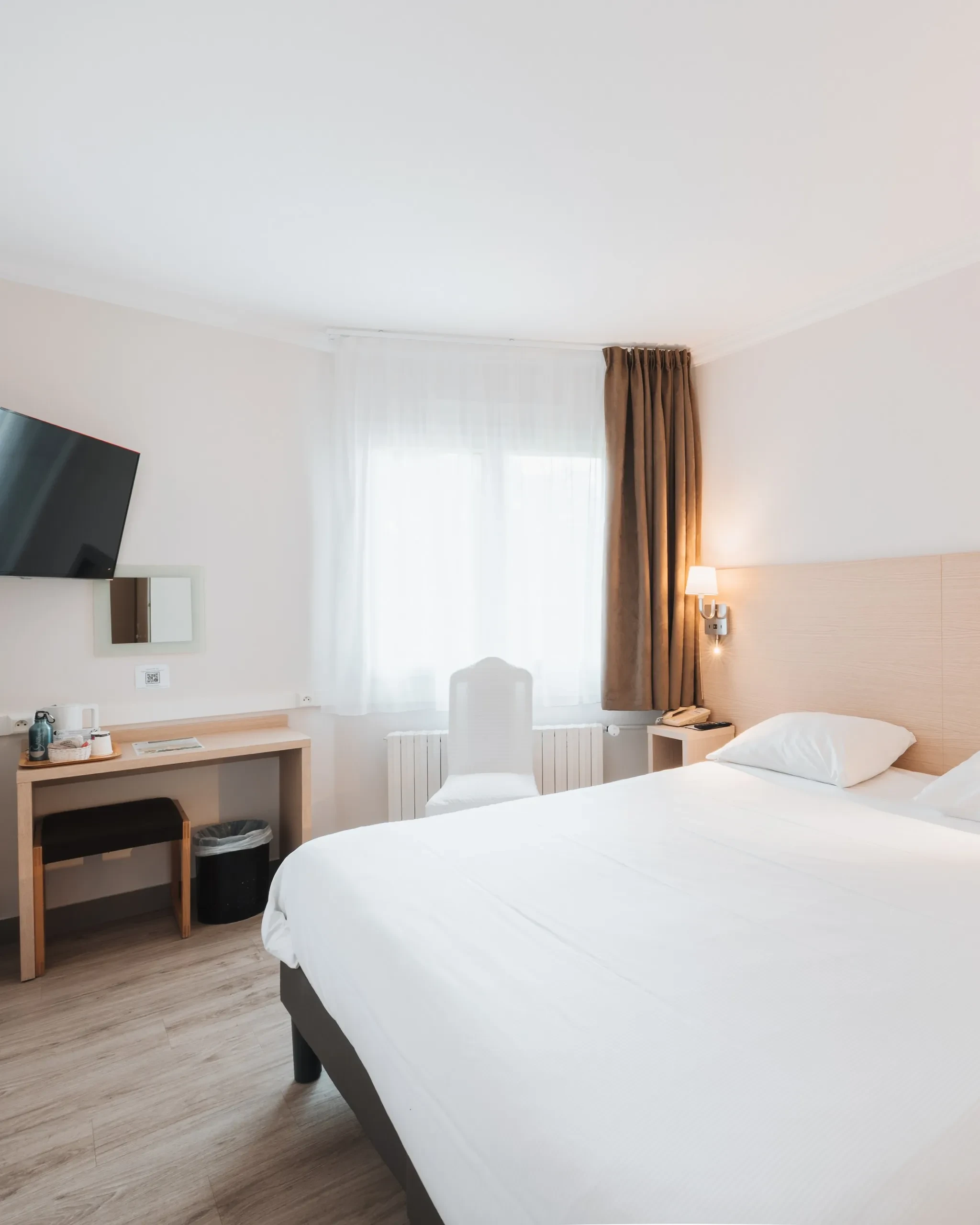 Chambre d’hôtel lumineuse avec lit double et bureau
