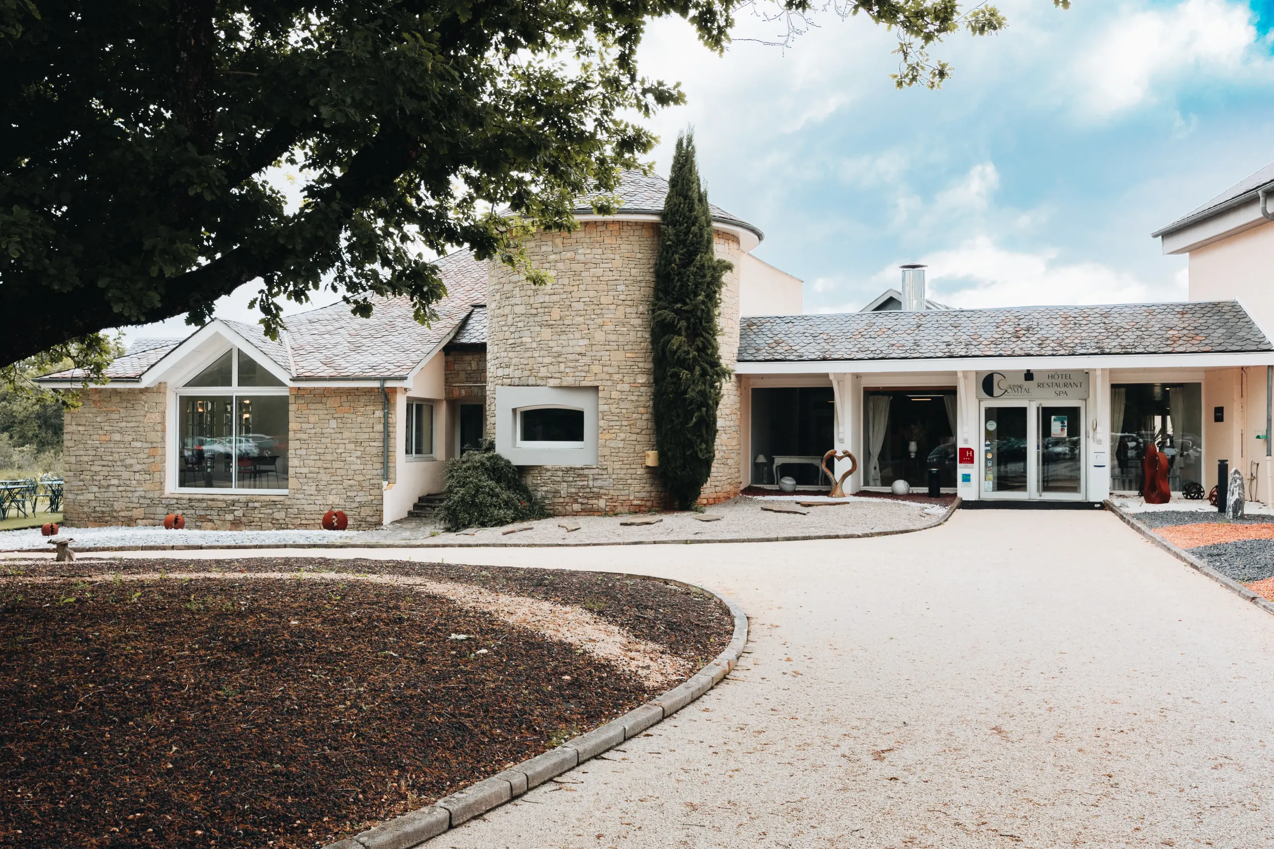 Entrée d’un hôtel-restaurant en pierre avec allée.